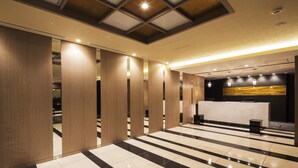 Un hall d’hôtel moderne avec un comptoir d’enregistrement, des cloisons en panneaux de bois et un sol à carreaux.