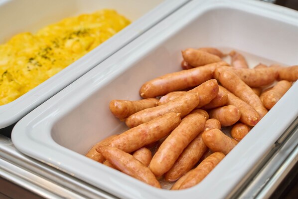 A buffet with a container of sausages and a container of scrambled eggs. - Hotel WBF Namba Motomachi (Osaka)