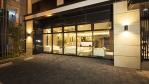 L’entrée d’un hôtel, avec un comptoir d’accueil, un espace salon et une façade en verre.
