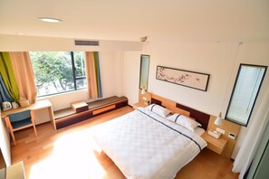 A modern bedroom with a large bed, a bedside table, a nightstand, a window with curtains, and a small seating area with a bench and a chair. - Ease Hostel (Guilin)