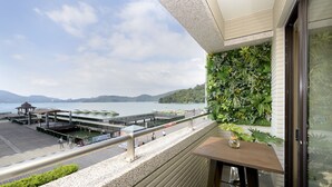 A balcony with a view of a waterfront, a wooden table, and a railing. - Hu Yue Lakeview Hotel (Yuchi)