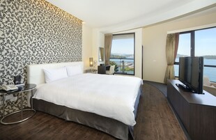 Habitación de hotel con una cama grande, televisión, escritorio y vista a un cuerpo de agua.