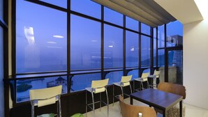 A modern dining area with large windows, a table, chairs, and potted plants. - Hu Yue Lakeview Hotel (Yuchi)