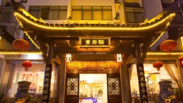 Une entrée de bâtiment de style chinois traditionnel, ornée de décorations élaborées et surmontée d’une enseigne.