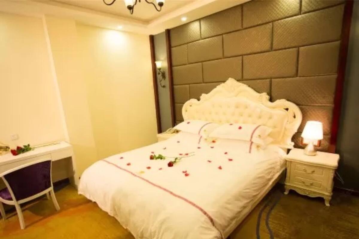 Un dormitorio con una cama grande, una mesita de noche con lámpara, una silla y un escritorio.