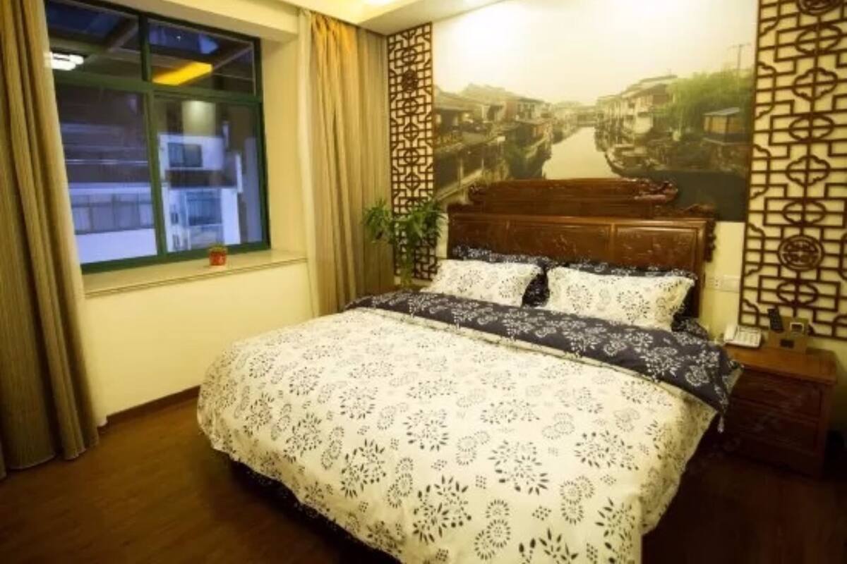 Un dormitorio con cama, ventana, panel decorativo en la pared y mesita de noche.