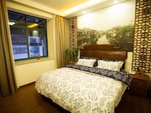 A bedroom with a bed, a window, a wall with a decorative panel, and a nightstand. - Huangshan Yiantang Hotel (Huangshan)