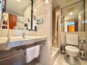 A modern bathroom with a large mirror, a sink, a toilet, and a shower area.