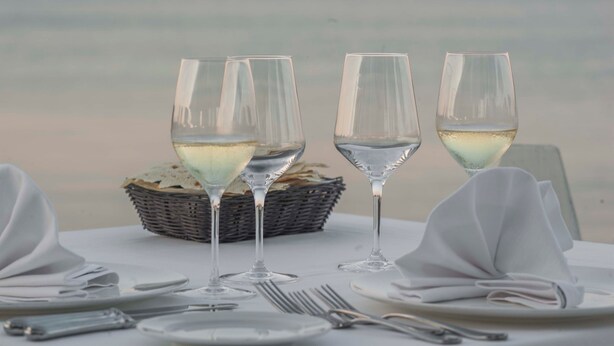 A table set for four with wine glasses and a basket. - Coluccia Hotel & Beach Club (Santa Teresa di Gallura)