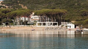 A coastal hotel with a beach, umbrellas, and boats. - Coluccia Hotel & Beach Club (Santa Teresa di Gallura)