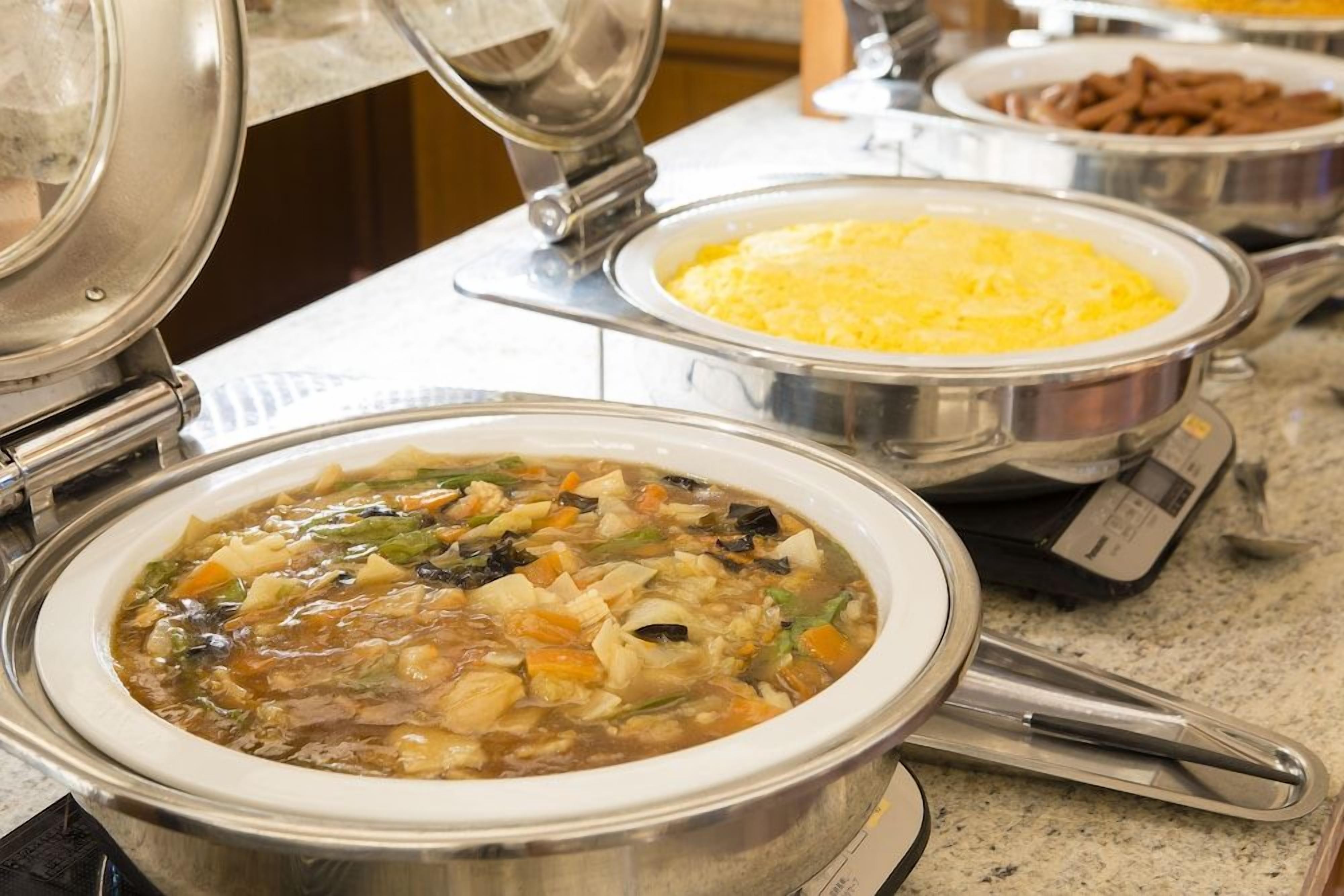 A buffet with various dishes including a soup, rice, and meat.