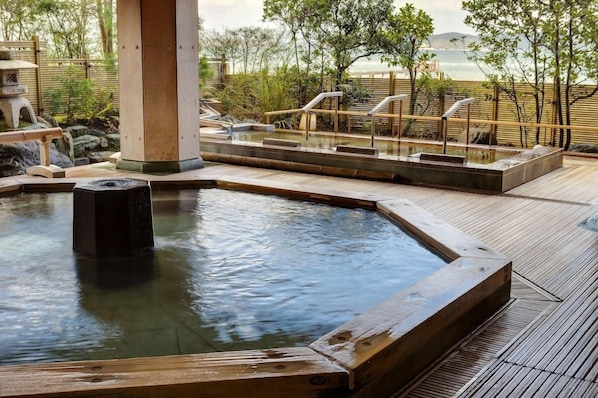 A wooden deck with a hot spring area, including a stone basin and a wooden platform.