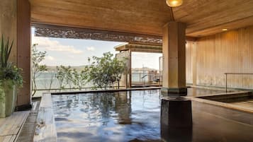 A spa area with a hot tub, wooden ceiling, and a view of the sea.