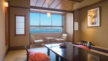 Quarto japonês tradicional com tatames, uma mesa baixa e vista para o mar.