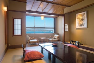 Una habitación japonesa tradicional con suelo de tatami, una mesa baja y vista al mar.