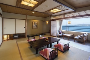 A traditional Japanese room with tatami flooring, a low table, and seating.
