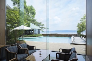Habitación con vistas a una piscina y una playa, amueblada con sillas y una mesa.