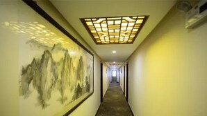 Un couloir doté d’un plafond au décor traditionnel, d’un sol recouvert de moquette et d’un grand tableau accroché au mur.