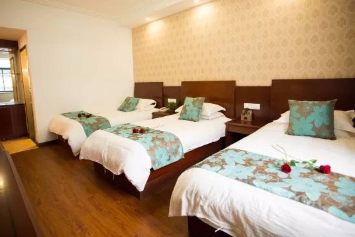 A hotel room with three single beds, each with a floral bedspread and matching pillows.