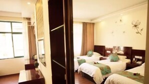 Une chambre d’hôtel avec trois lits, un bureau et un grand miroir.