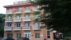 A multi-story building with balconies, a garage door, and a heart-shaped light decoration. - Gangchon Sweet Pension (Chuncheon)