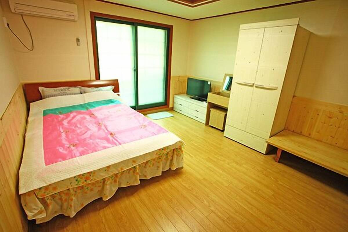 A bedroom with a bed, a television, a wardrobe, and a bench.