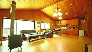 A spacious living room with a fireplace, wooden flooring, and a high ceiling with wooden beams. - Blue Sky Pension (Pocheon)