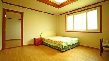 Quarto com cama, mesa de cabeceira, cadeira, janela e porta.
