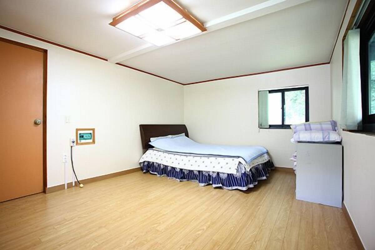 A bedroom with a bed, a window, and a door.