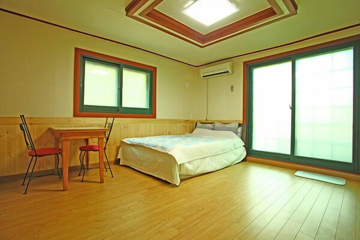 A bedroom with a bed, a desk, and two chairs.