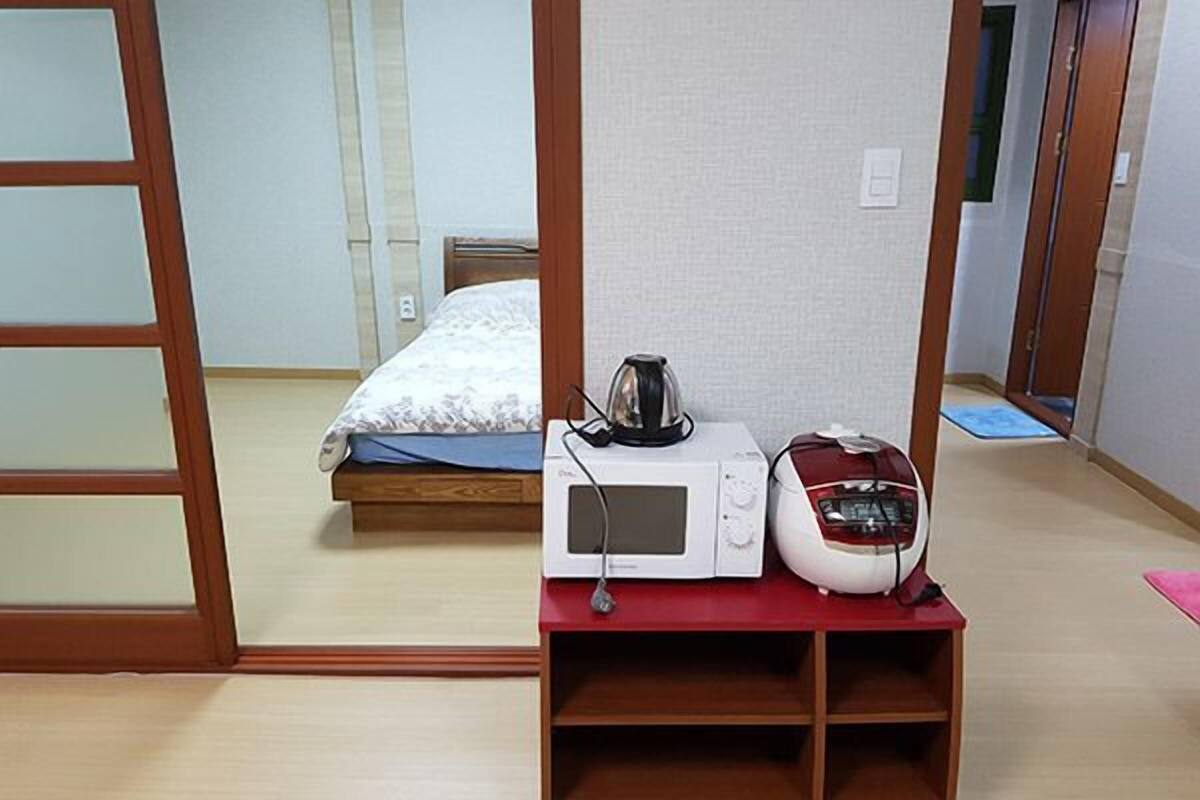A room with a bed, a microwave, and a radio on a small table.
