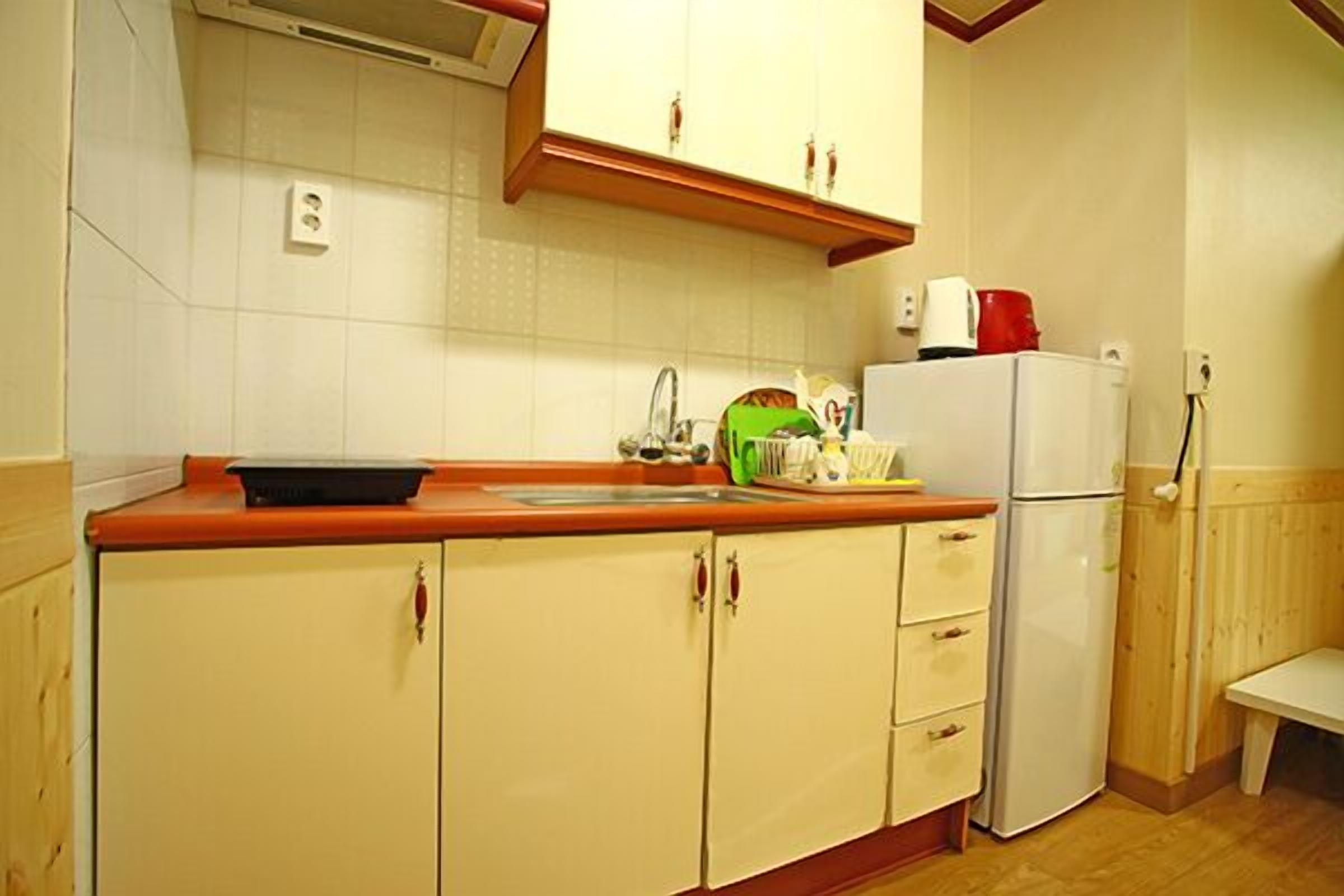 A compact kitchen with white cabinets, a red countertop, and a white refrigerator.