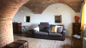 Un salon avec un plafond en briques, un canapé, un meuble en bois et une petite table.