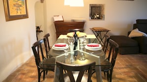 Un espace repas avec une table en verre, des chaises en bois et un plafond en briques.
