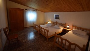 A bedroom with two wooden beds, a wooden wardrobe, a chair, and a window with curtains. - Comfortable apartment with balcony (Pag)