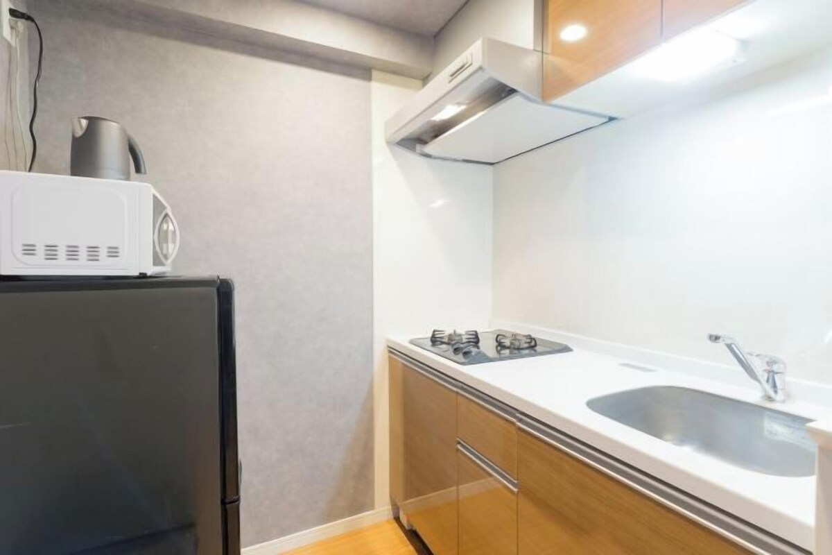 A compact kitchen with a microwave, stove, and sink.