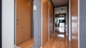A hallway with wooden flooring and grey walls, leading to a kitchen area with a black countertop and a window. - Residence Hotel Hakata 8 (Fukuoka)