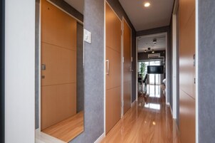 Un pasillo con suelo de madera y paredes grises, que conduce a una zona de cocina con encimera negra y una ventana.