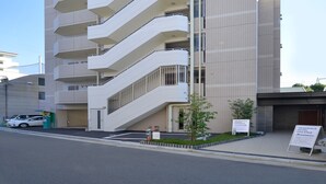 A modern hotel with a unique zigzag facade, multiple balconies, and a clear sky. - Residence Hotel Hakata 8 (Fukuoka)