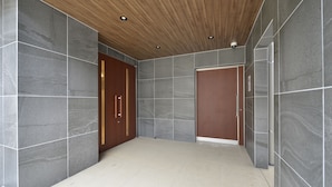 A modern hallway with grey stone walls, wooden ceiling, and a tiled floor. - Residence Hotel Hakata 8 (Fukuoka)