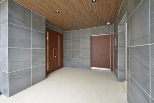 Un pasillo moderno con paredes de piedra gris, techo de madera y suelo de baldosas.