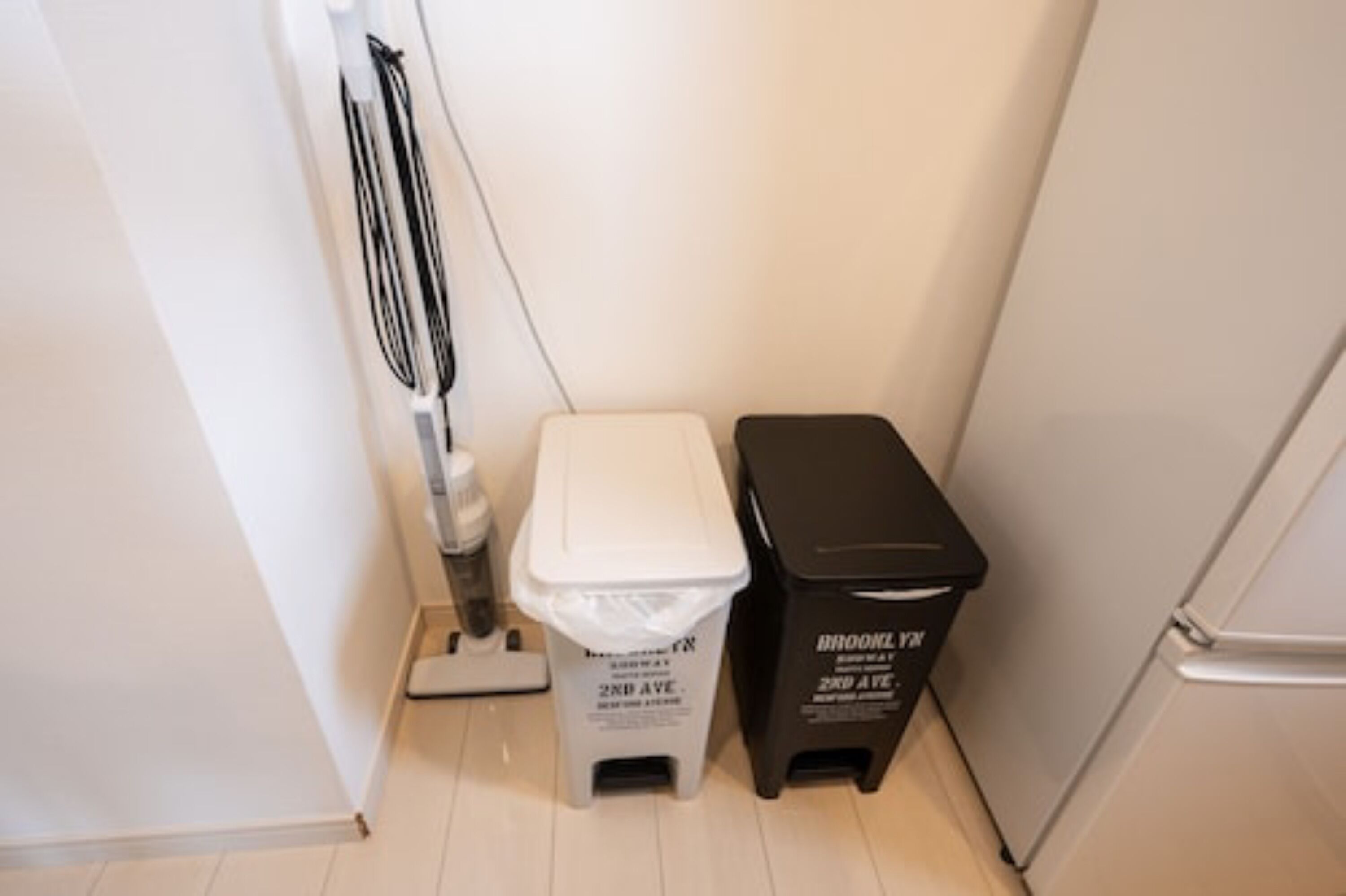 Une petite salle de bain avec des toilettes, une poubelle et un balai.