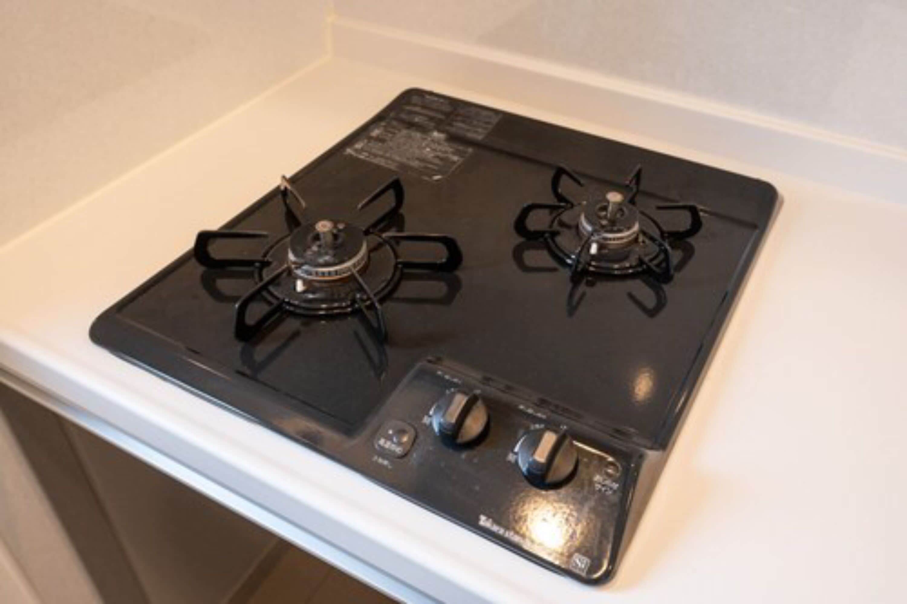 A black gas stove with two burners and a control panel with knobs.