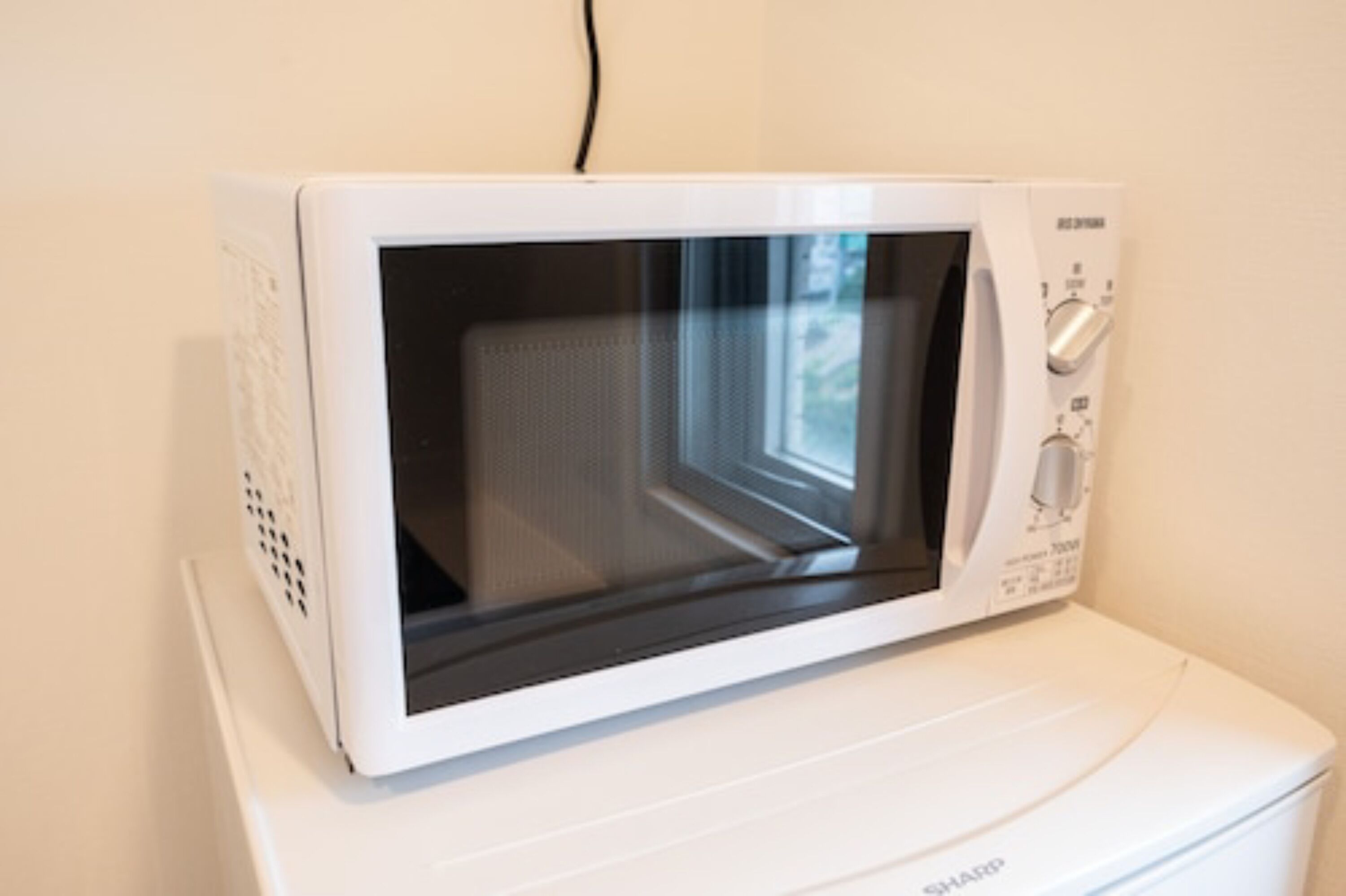 Un horno microondas blanco sobre una base blanca para electrodomésticos.