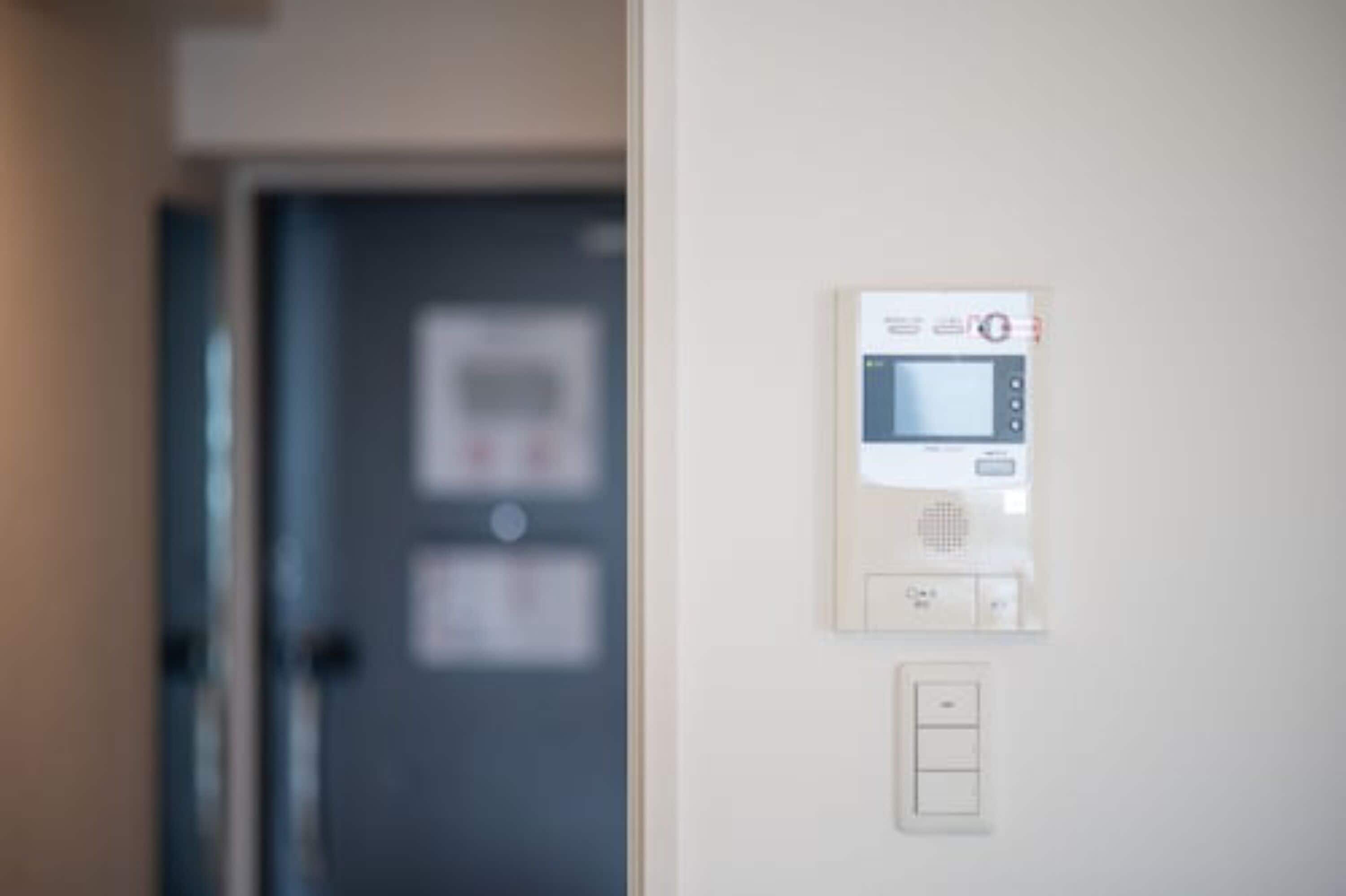 A wall-mounted control panel with a digital display and buttons, likely for room amenities.