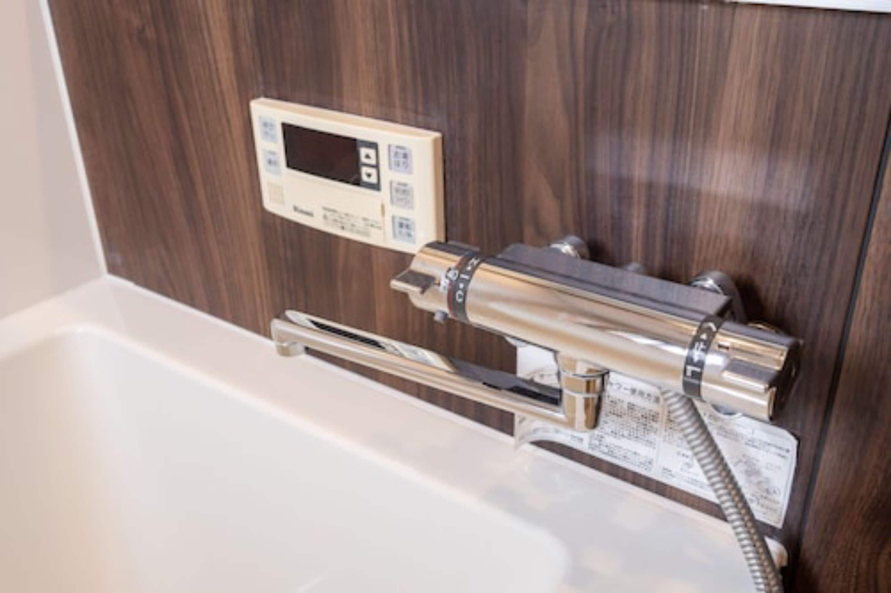 Une salle de bain moderne dotée d’un panneau de commande numérique intégré, situé au-dessus de la baignoire.