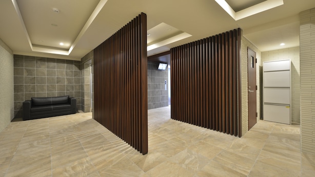A modern hotel lobby with a black leather sofa, wooden partitions, and a tiled floor. - Residence Hotel Hakata 8 (Fukuoka)