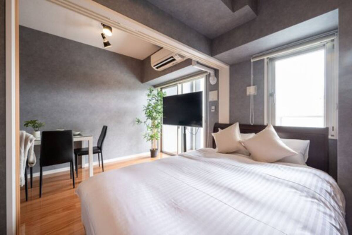 A modern bedroom with a large bed, a desk, and a TV.