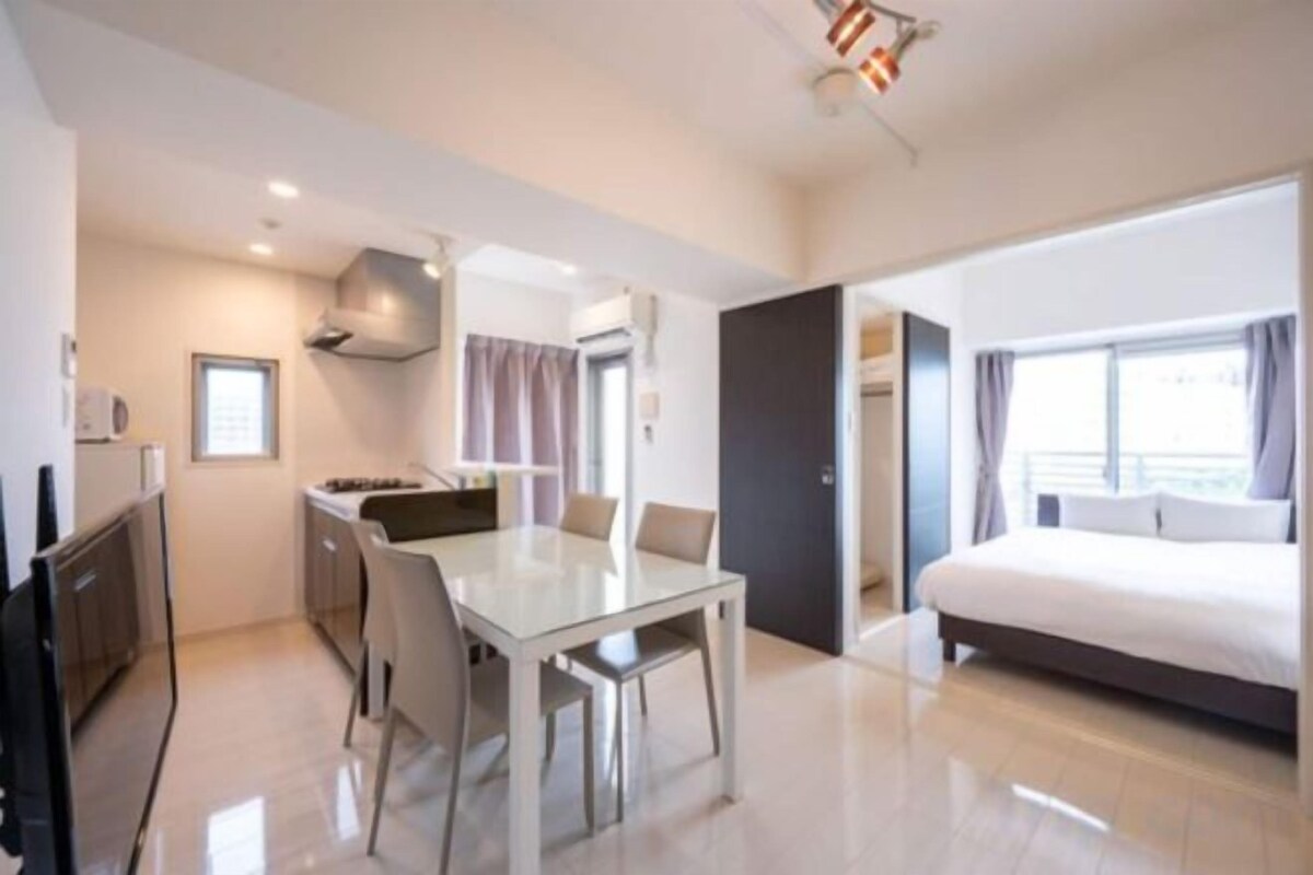 Una habitació d'hotel moderna amb un llit gran, una zona de menjador separada i una cuineta.
