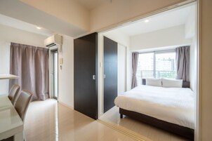 Una habitación de hotel moderna con una cama grande, un escritorio y un armario.